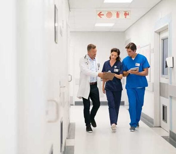 healthcare-cs-2 Medical staff in surgical attire, including masks and caps, standing and working together in a clinical setting